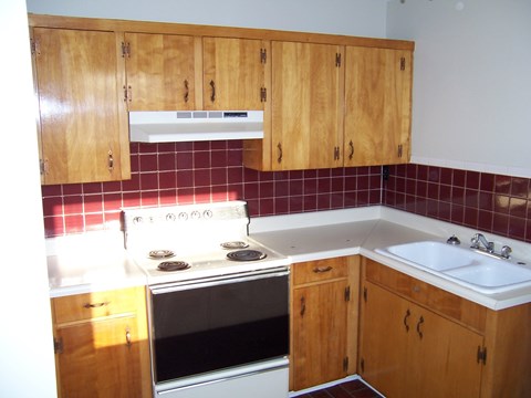 A kitchen with wooden cabinets and a stove top oven.