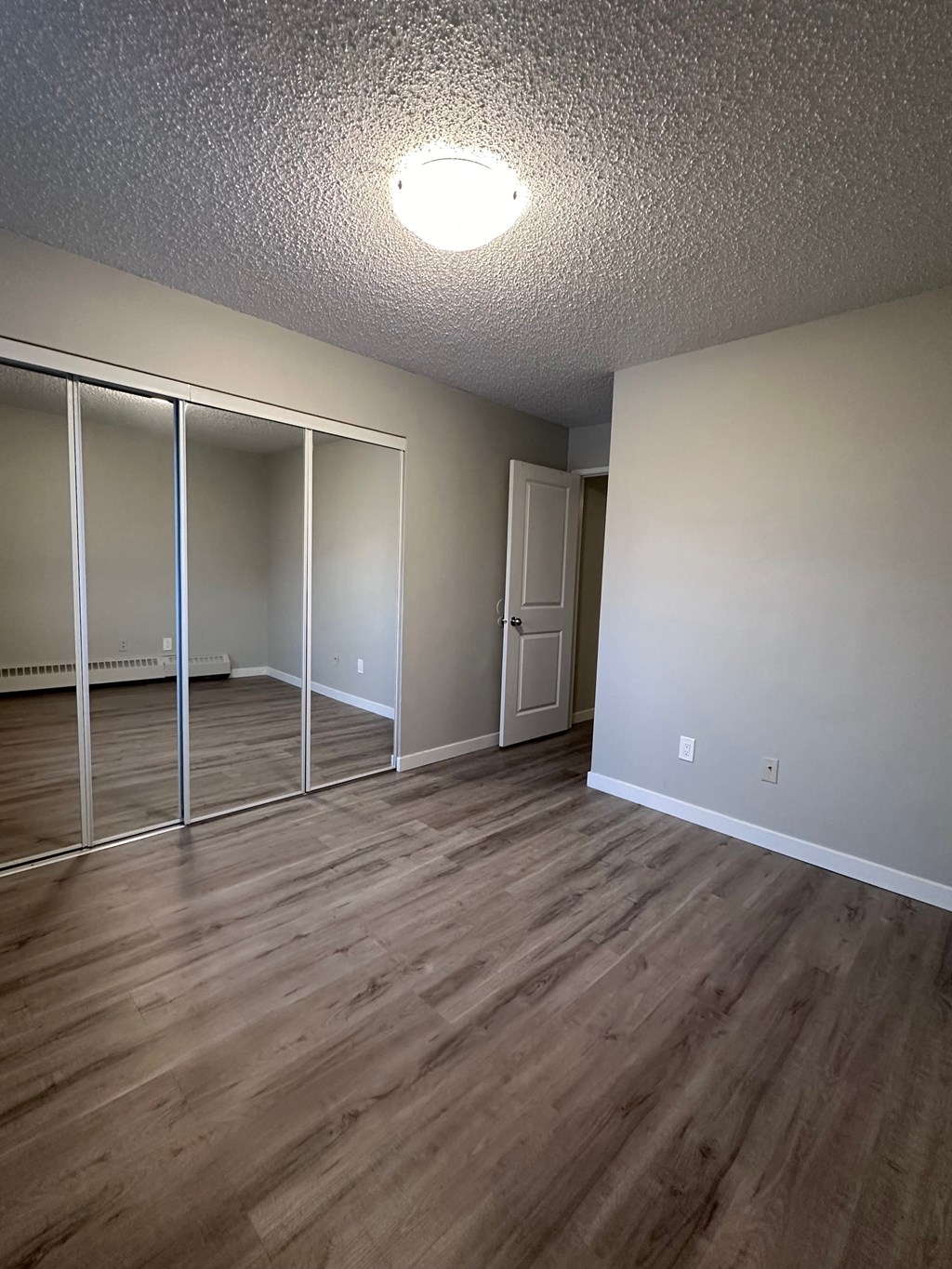 an empty living room with wood floors and mirrored closet doors