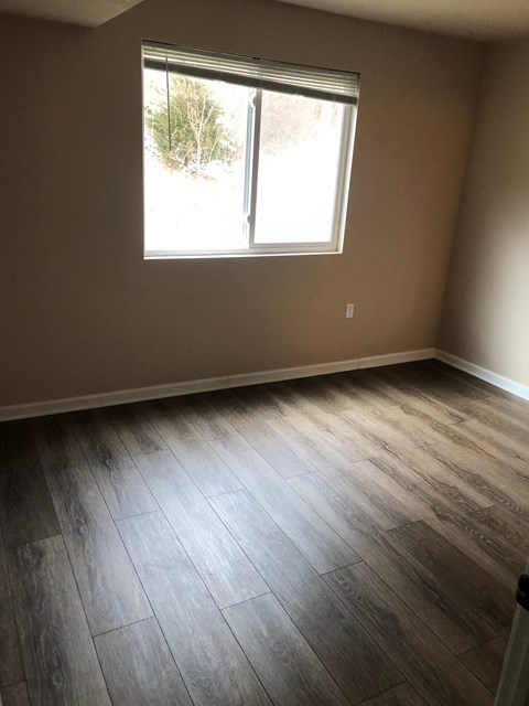 A room with a window and wooden flooring.