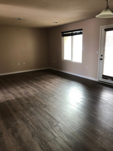 A room with wooden flooring and a window with blinds.