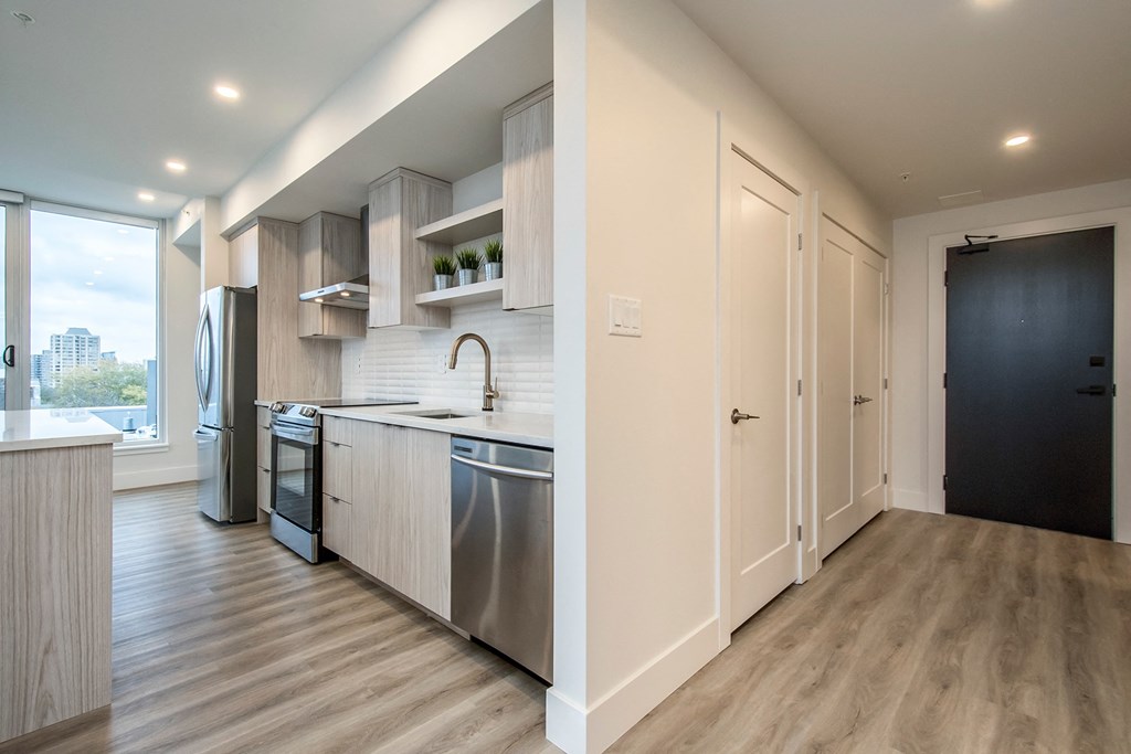a kitchen with stainless steel appliances and wooden flooring in an apartment