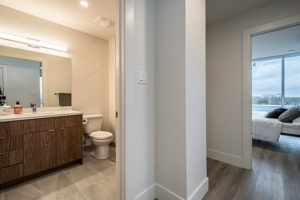 a bathroom with a toilet and a sink and a bedroom