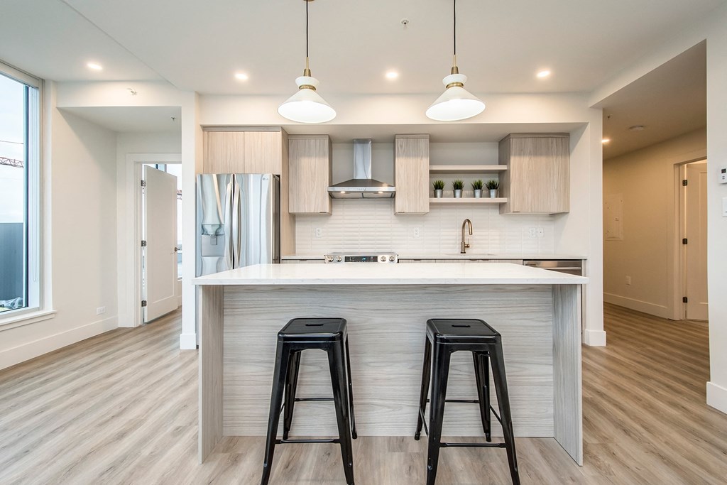 a kitchen with two bar stools in front of a large island with a counter