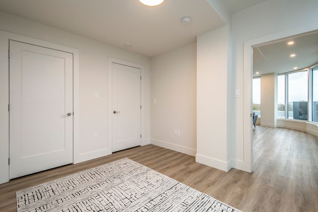 an empty living room with white doors and a rug