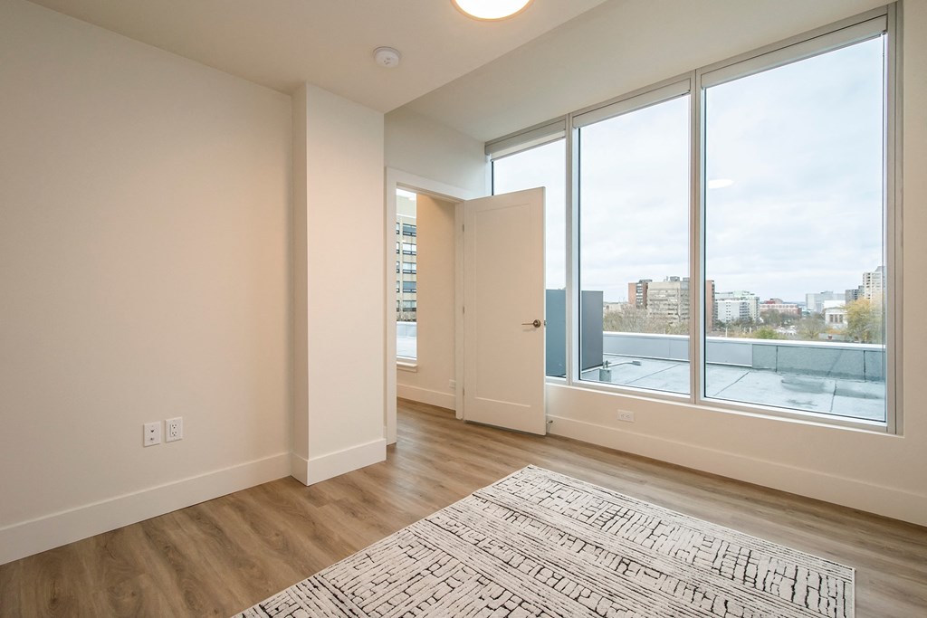 an empty living room with a large window and a rug