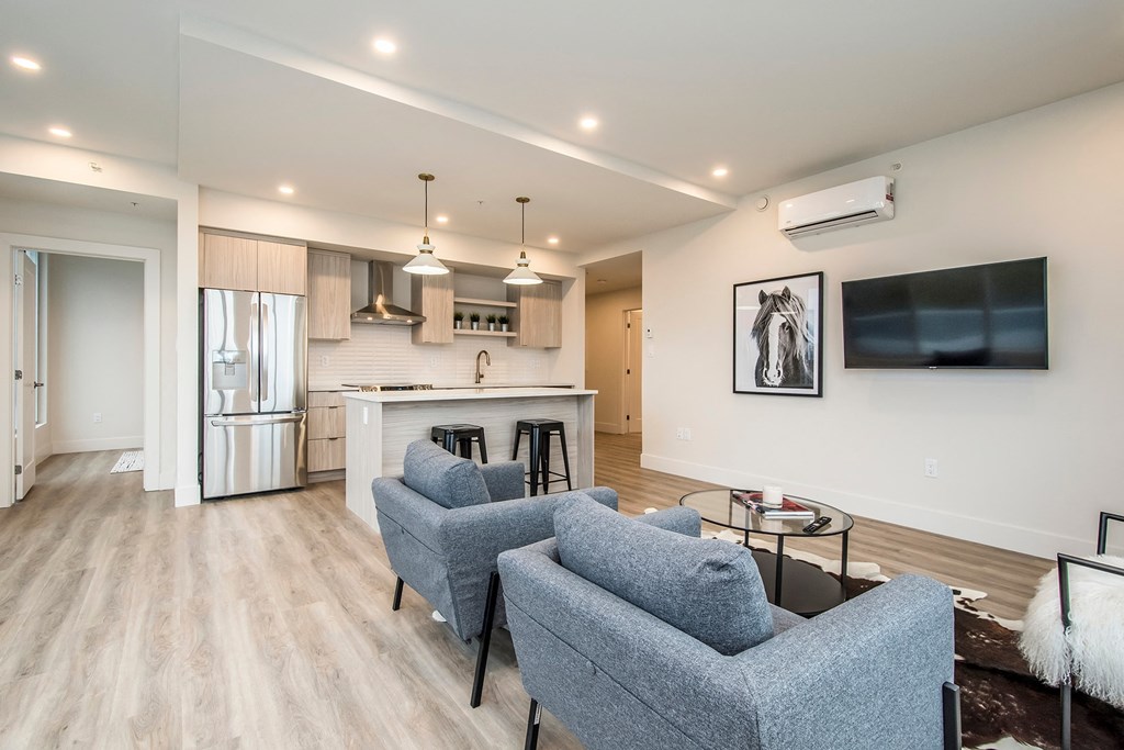 a living room with couches and a table and a kitchen