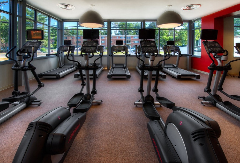 a gym full of cardio equipment and windows in a building