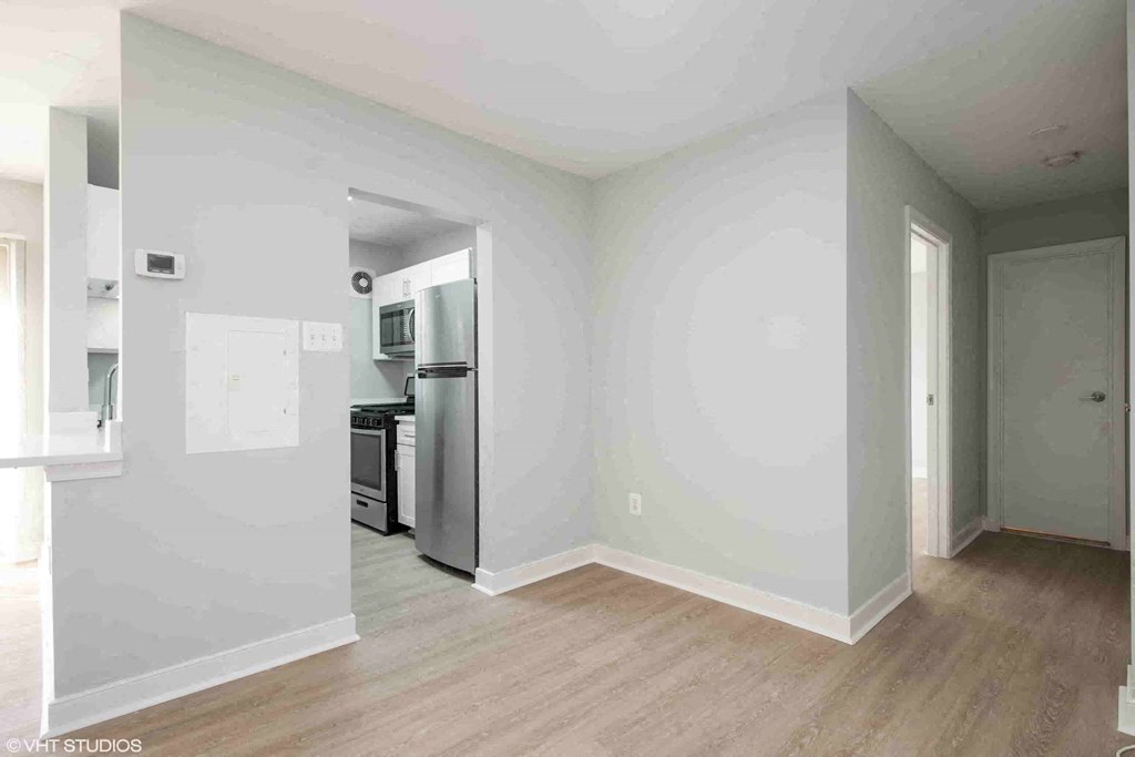 an empty living room and kitchen with white walls and wood floors
