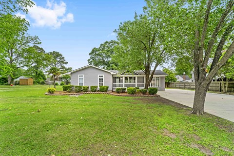 a gray house with trees and grass in front of it