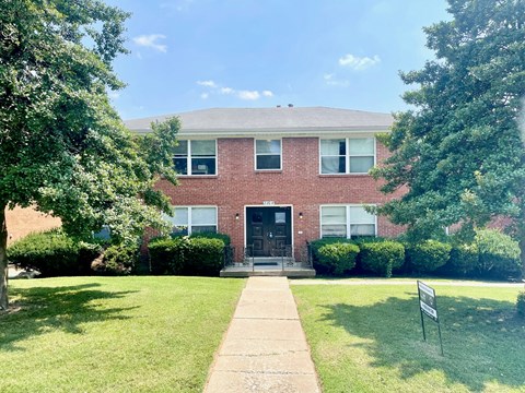 a brick house with a lawn and trees in front of it