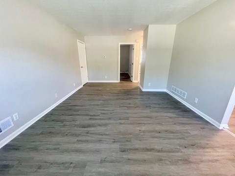 a empty living room with wood flooring and white walls