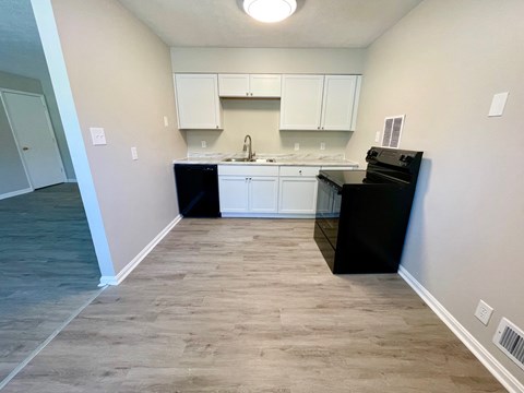 an empty kitchen with white cabinets and a black counter top