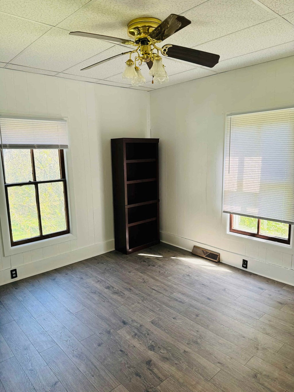 an empty living room with wood floors and a ceiling fan