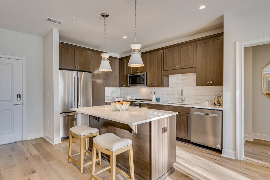 A kitchen with a white island and wooden bar stools.