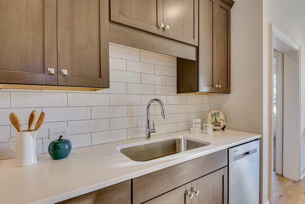 A kitchen with a white countertop and a stainless steel sink.