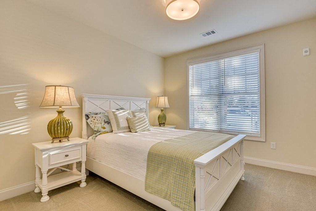 A bedroom with a bed, nightstand, and lamp.