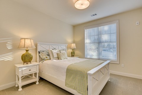 A bedroom with a bed, nightstand, and lamp.