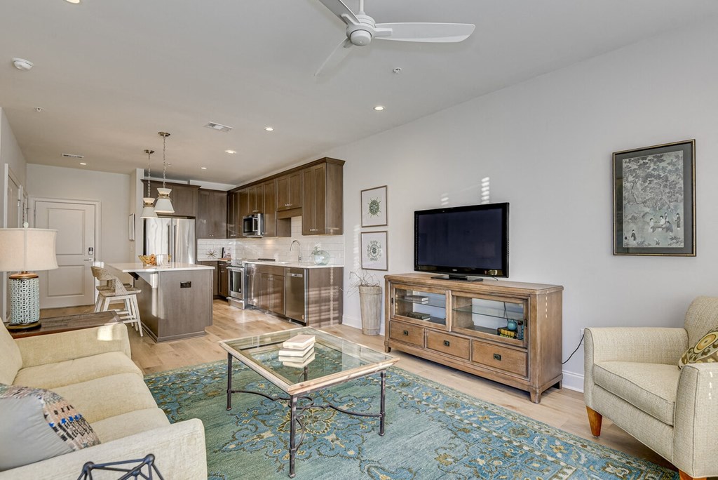 A living room with a glass coffee table and a television on a wooden cabinet.