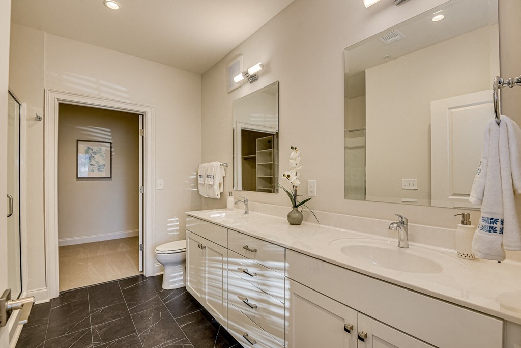 A bathroom with a toilet, sink, and mirror.