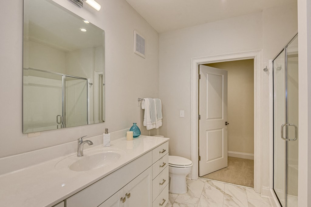 A white bathroom with a sink, toilet, and shower.