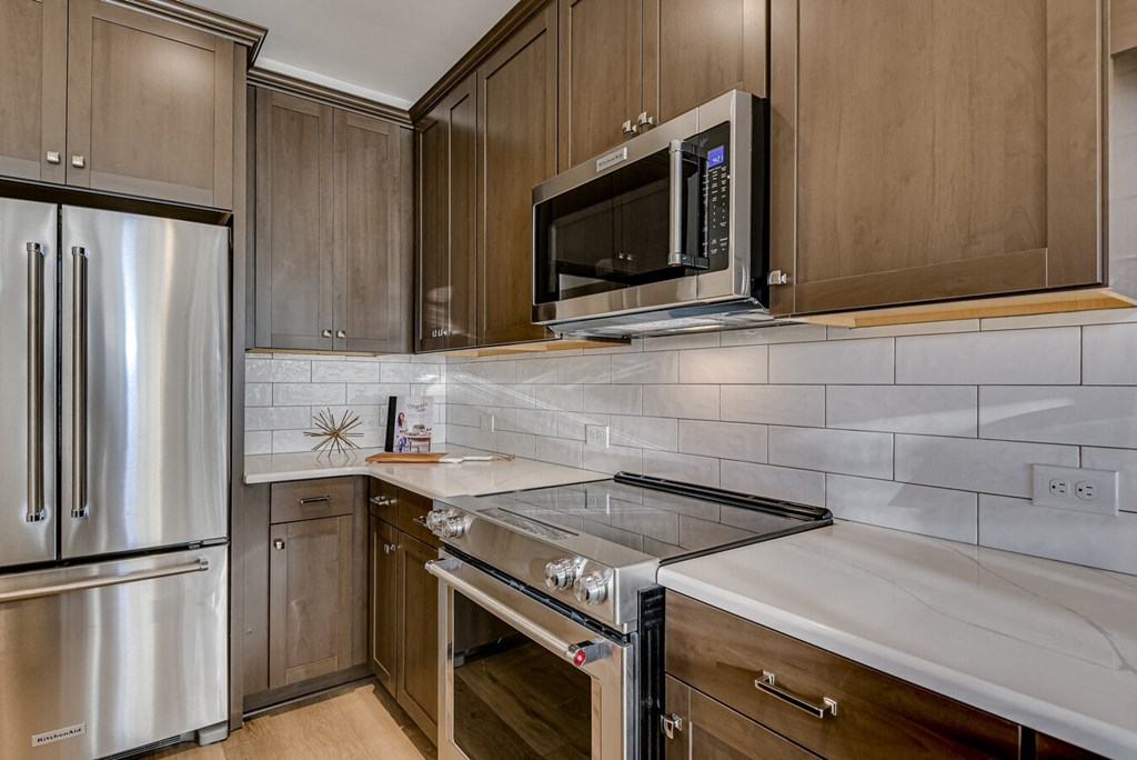 A modern kitchen with wooden cabinets and a stainless steel refrigerator.