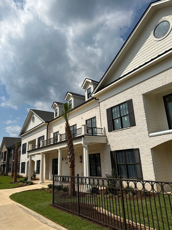 A white building with black railings and a black fence.