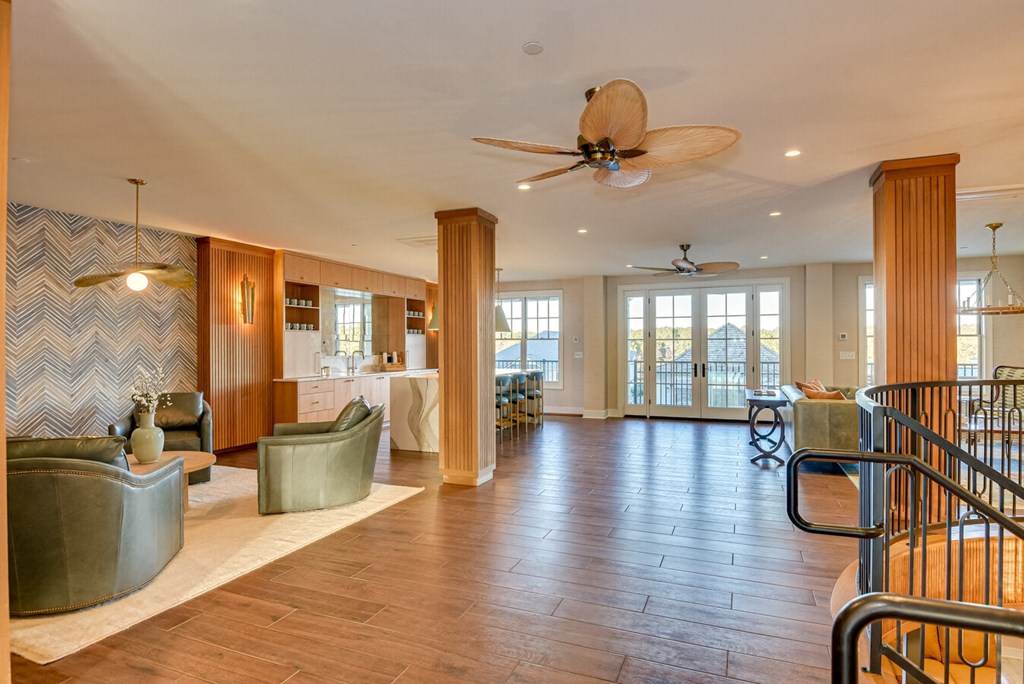 A spacious living room with a ceiling fan and hardwood floors.