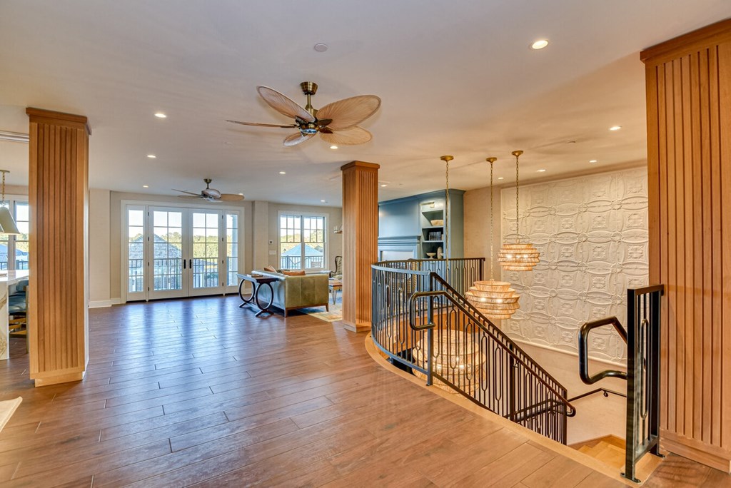 A spacious living room with a staircase and a ceiling fan.