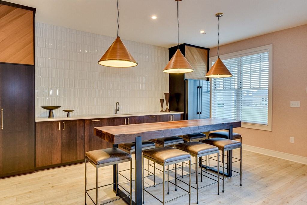 A kitchen with a wooden table and bar stools.