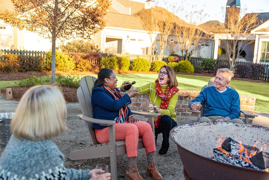 A group of people sitting around a fire pit in a backyard.