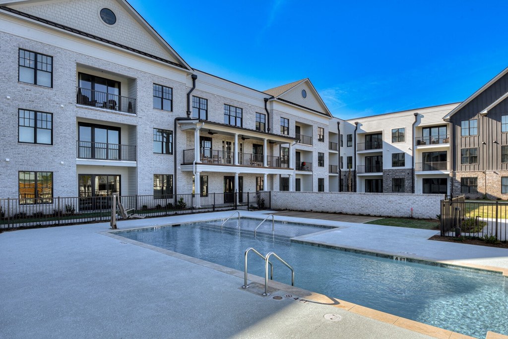A swimming pool is located in front of a building with multiple balconies.