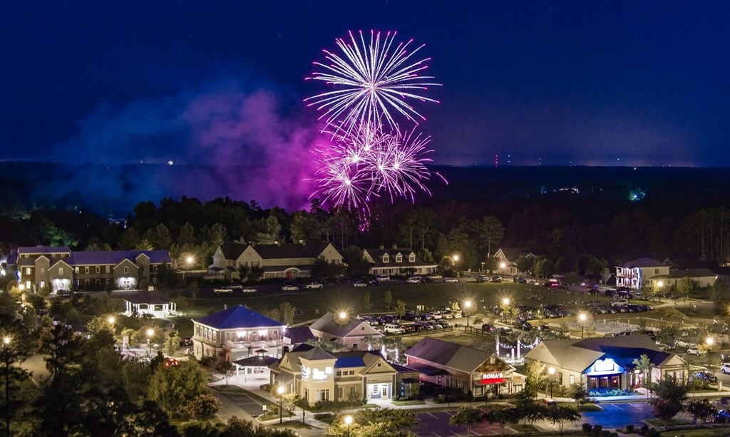 A nighttime view of a town with buildings and a fireworks display.