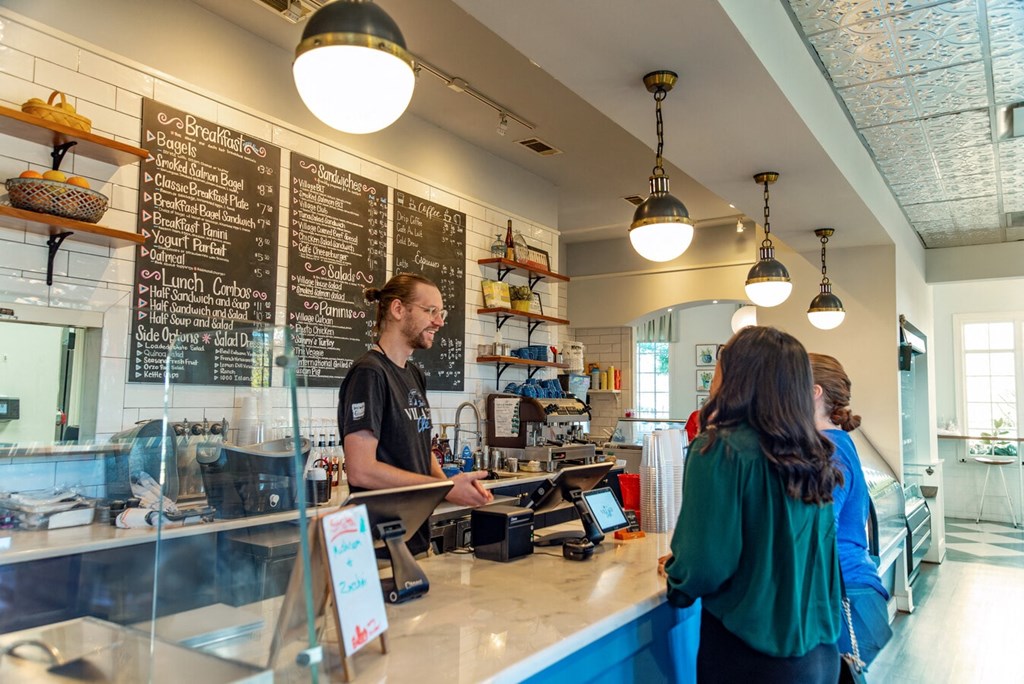 A man is standing behind a counter in a restaurant.