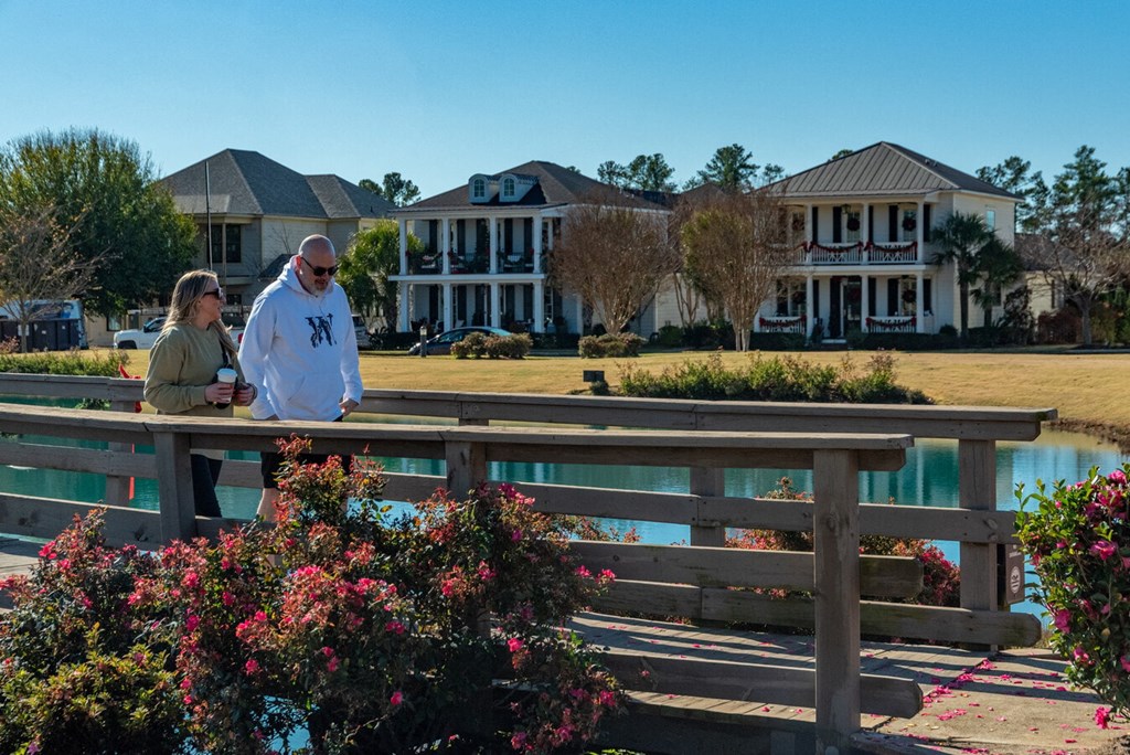Two people are standing on a wooden bridge over a pond.