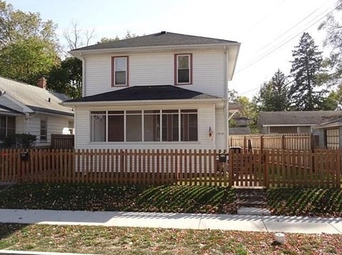 A white house with a brown fence in front.