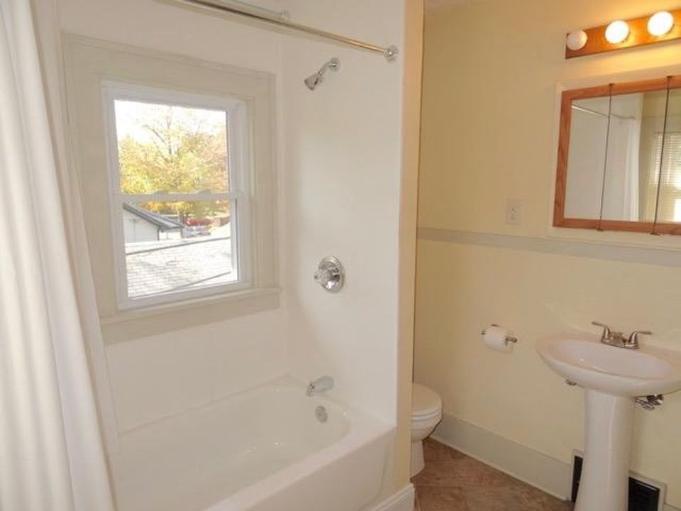 A bathroom with a white tub, sink, and toilet.