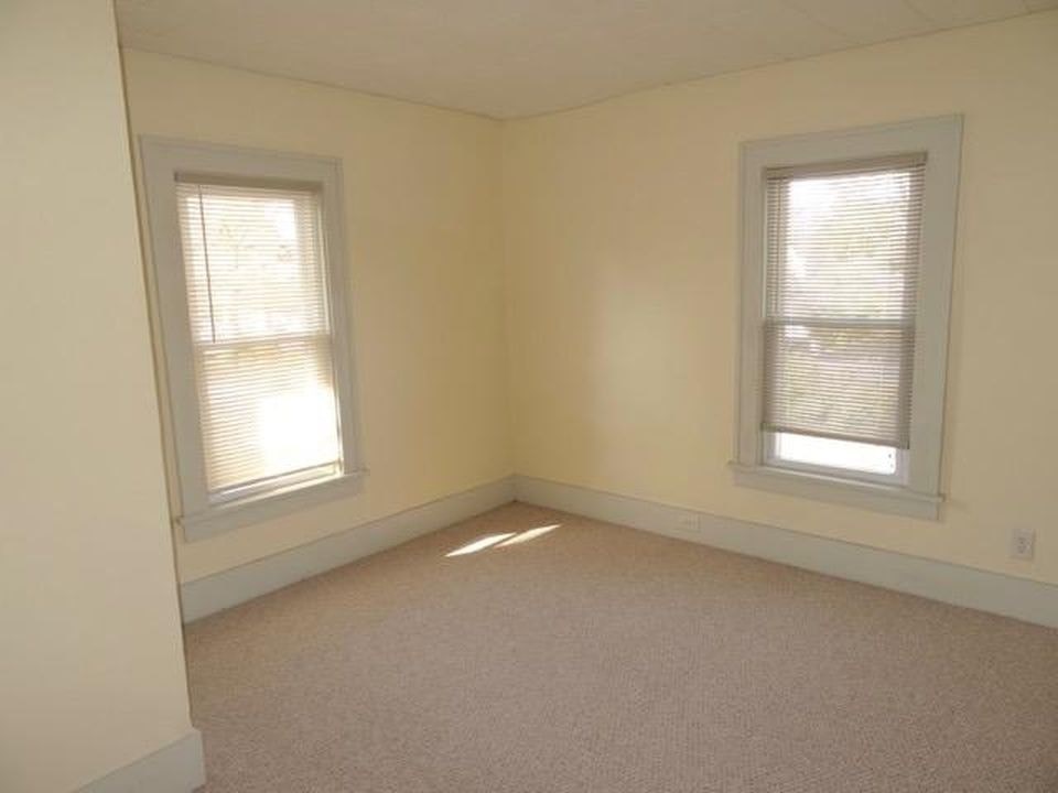 A room with two windows and carpeted floor.