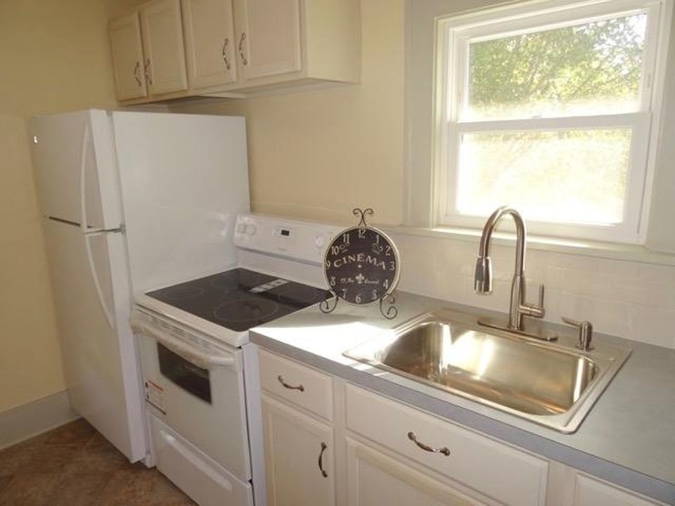 A kitchen with white appliances and a window.