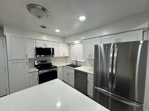 a white kitchen with a stainless steel refrigerator