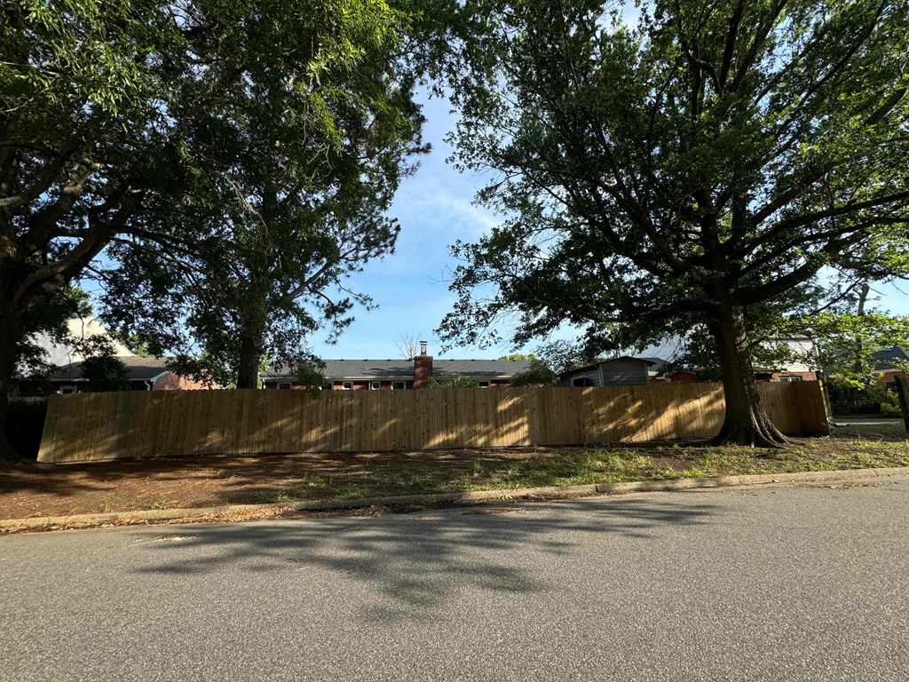 a fence between two trees on the side of a street