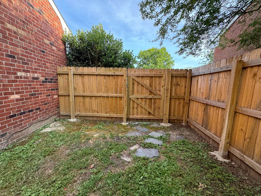 a wooden fence in a backyard next to a brick wall
