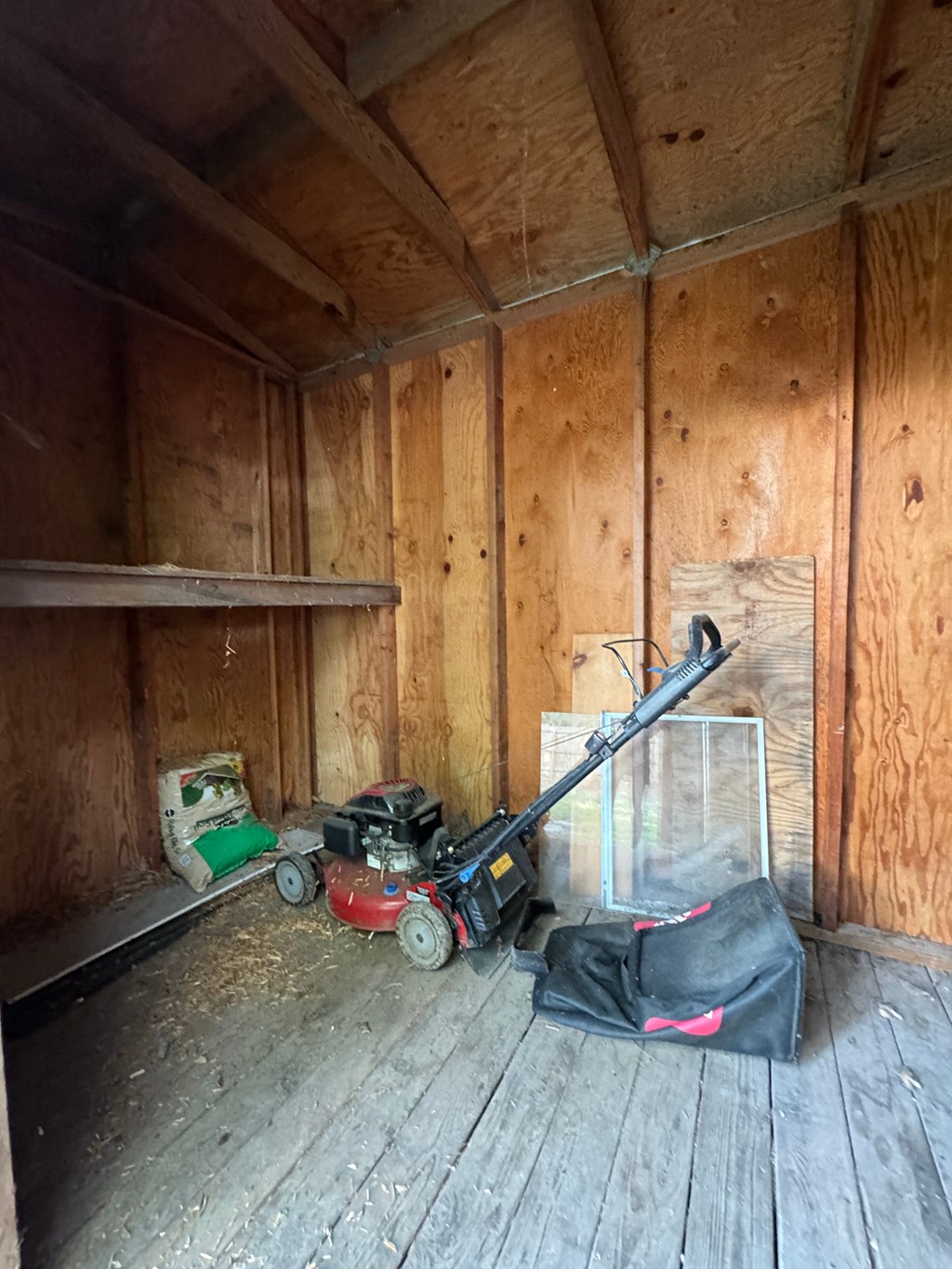 the inside of a wooden shed with tools on the floor