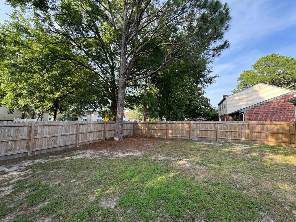 a fenced in backyard with a tree and a house
