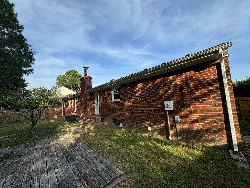 the back of a brick house with a wooden deck