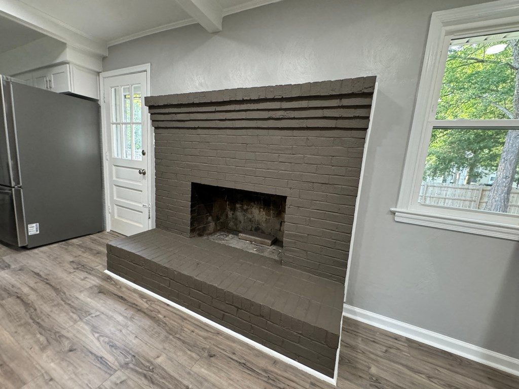 a living room with a brick fireplace and wooden floors