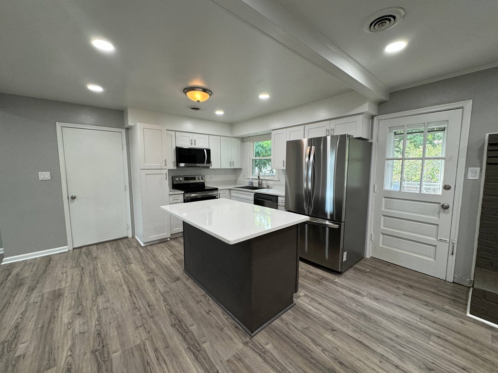 a kitchen with a center island and a stainless steel refrigerator