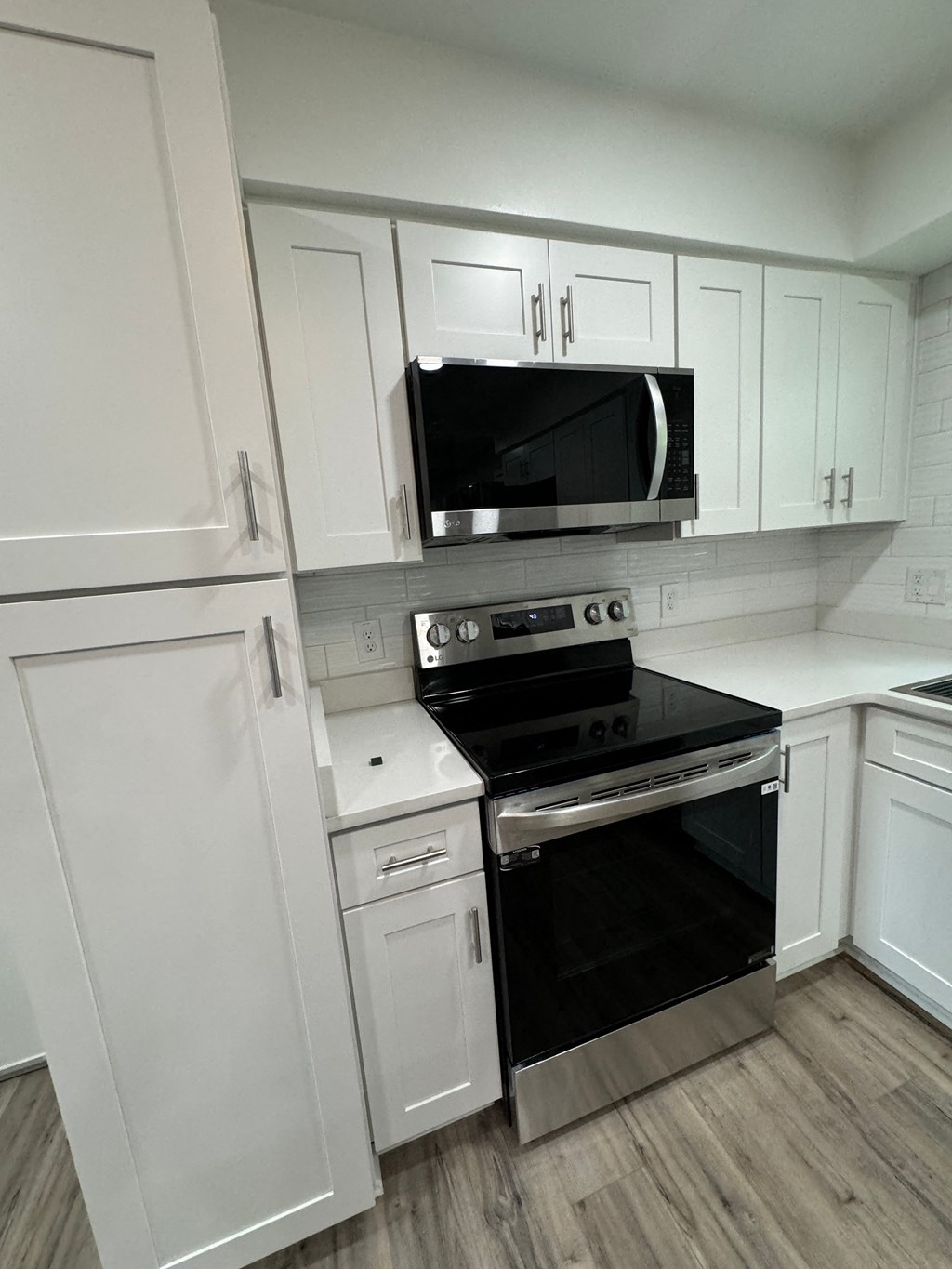 a kitchen with white cabinets and a stove and a microwave