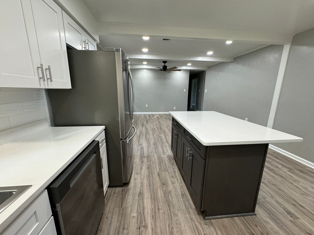 a kitchen with white counter tops and a stainless steel refrigerator