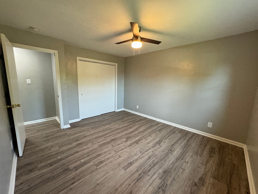 a empty living room with wood floors and a ceiling fan