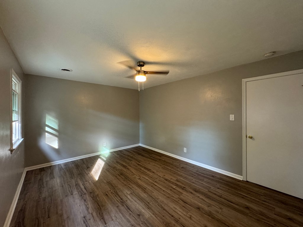 an empty living room with wood floors and a ceiling fan